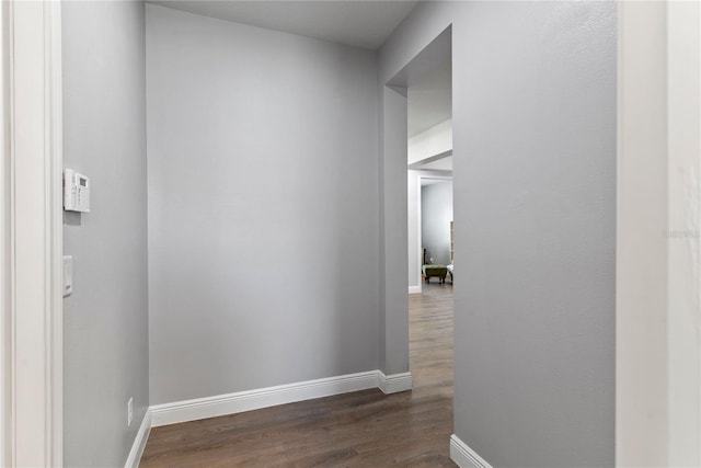 corridor with dark wood-style flooring and baseboards