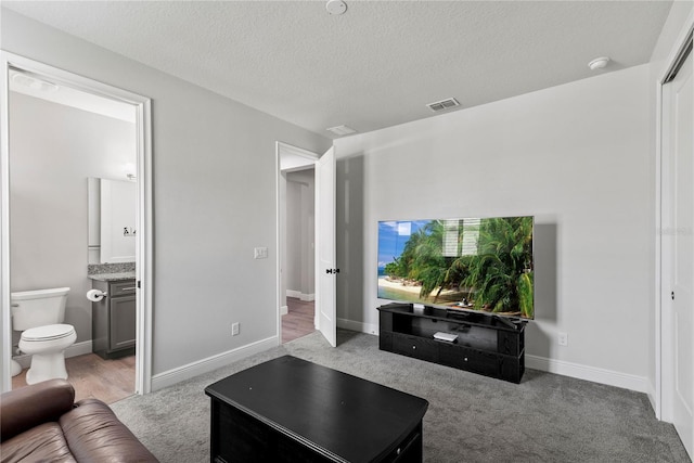 living room featuring carpet flooring, a textured ceiling, and visible vents