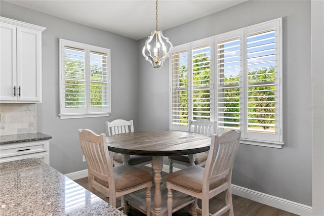 dining space with baseboards, a chandelier, and dark wood finished floors