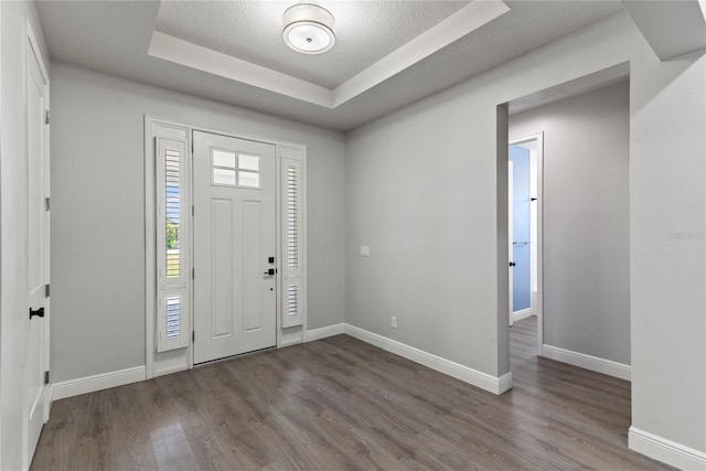 entryway with baseboards, a tray ceiling, and dark wood finished floors