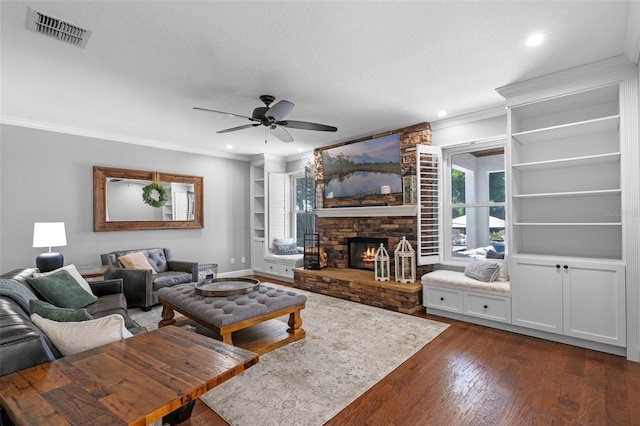 living room with ceiling fan, visible vents, built in features, ornamental molding, and dark wood-type flooring
