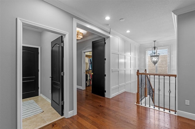 hall featuring crown molding, recessed lighting, baseboards, an upstairs landing, and wood finished floors