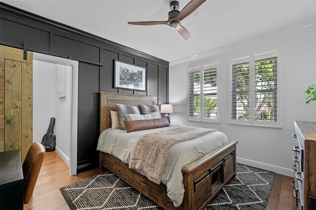 bedroom featuring crown molding, a ceiling fan, baseboards, and wood finished floors