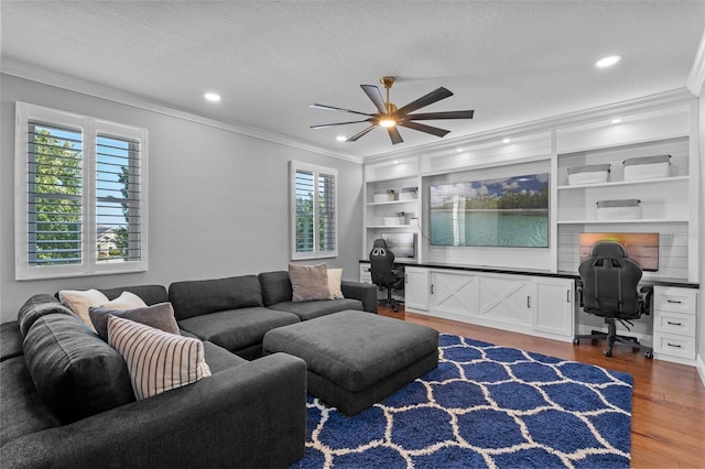 living area featuring crown molding, built in desk, a ceiling fan, and wood finished floors