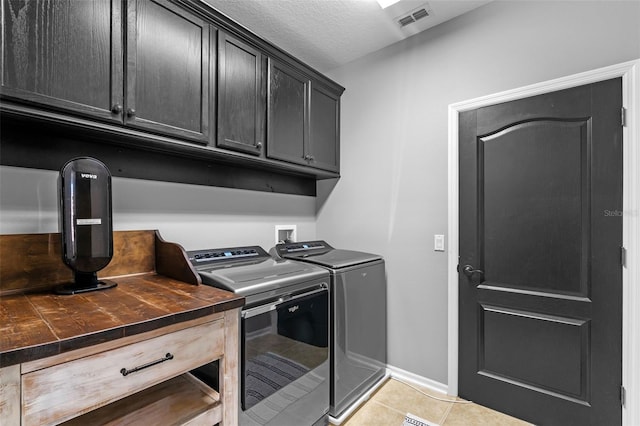 clothes washing area featuring visible vents, washer and dryer, baseboards, cabinet space, and light tile patterned floors