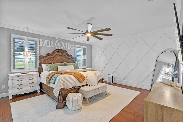 bedroom featuring crown molding, multiple windows, and a decorative wall