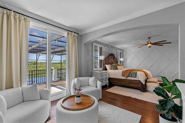 bedroom with arched walkways, ornamental molding, wood finished floors, and access to exterior