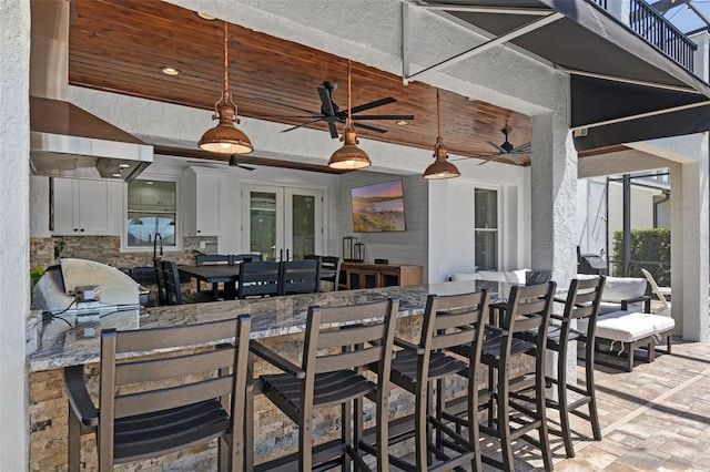 view of patio / terrace with ceiling fan, french doors, outdoor dining area, a balcony, and an outdoor kitchen