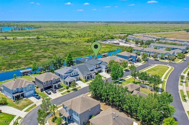 drone / aerial view featuring a wooded view, a water view, and a residential view