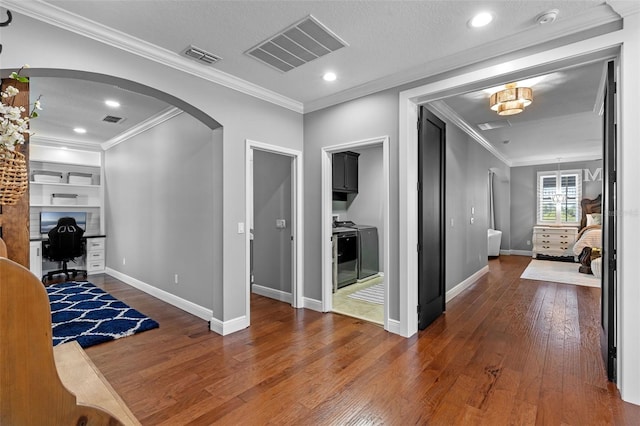 hallway featuring wood-type flooring, arched walkways, crown molding, and visible vents