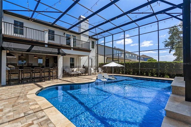 outdoor pool with outdoor dry bar, glass enclosure, ceiling fan, and a patio area