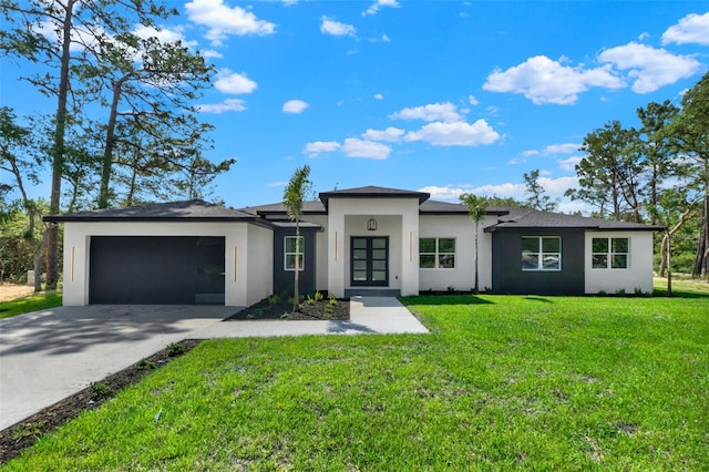 prairie-style house with an attached garage, stucco siding, a front yard, concrete driveway, and french doors
