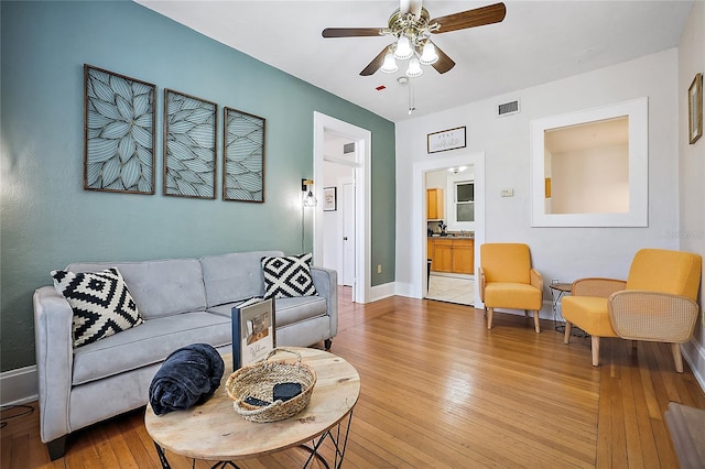 living room with visible vents, a ceiling fan, light wood-style flooring, and baseboards