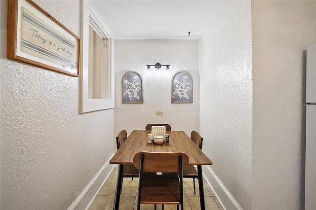 tiled dining space with baseboards and a textured wall