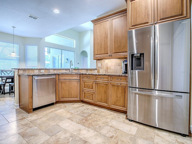 3775 Brantley Place Cir, Apopka, FL 32703 - kitchen featuring stainless steel appliances, light stone countertops, a peninsula, tasteful backsplash, and brown cabinetry
