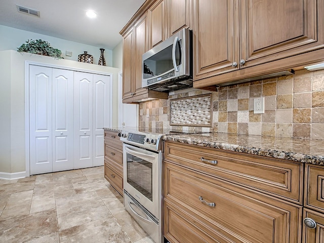 3775 Brantley Place Cir, Apopka, FL 32703 - kitchen with stainless steel appliances, dark stone countertops, decorative backsplash, baseboards, and light stone finish floors