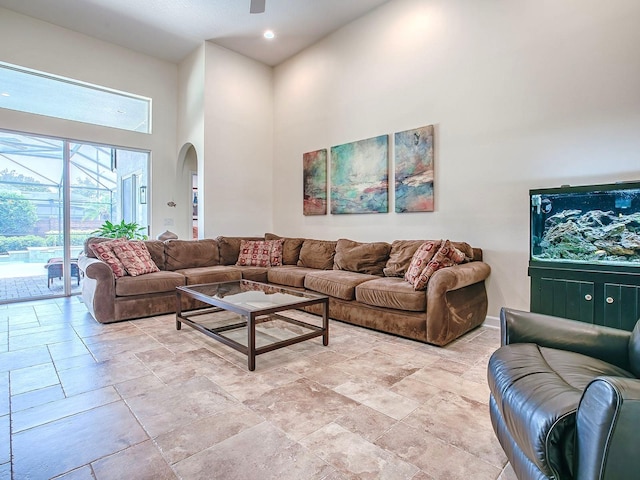 3775 Brantley Place Cir, Apopka, FL 32703 - living room with a towering ceiling, arched walkways, a ceiling fan, baseboards, and light stone finish flooring