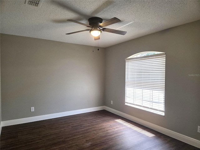 spare room with ceiling fan, dark wood-type flooring, baseboards, and a textured ceiling