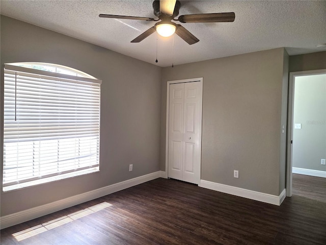 spare room with a ceiling fan, a textured ceiling, dark wood finished floors, and baseboards