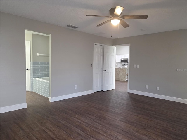 empty room featuring a ceiling fan, dark wood-type flooring, and baseboards