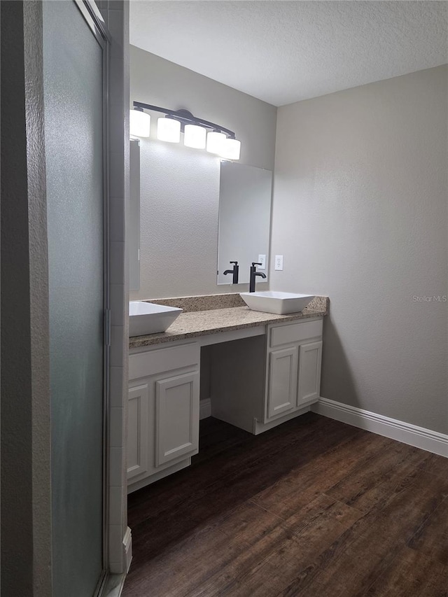 bathroom featuring wood finished floors, double vanity, and baseboards