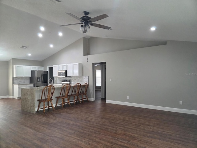 kitchen with stainless steel appliances, a peninsula, a breakfast bar, white cabinetry, and light countertops