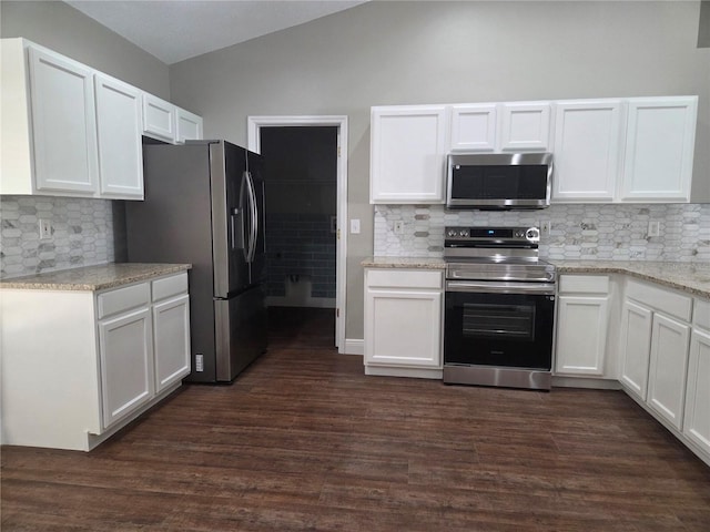 kitchen featuring appliances with stainless steel finishes, white cabinetry, lofted ceiling, dark wood-style flooring, and decorative backsplash