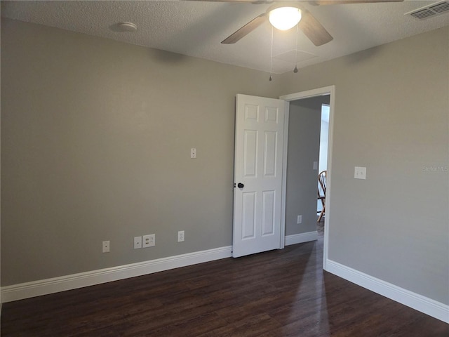 empty room featuring a ceiling fan, dark wood finished floors, baseboards, and a textured ceiling