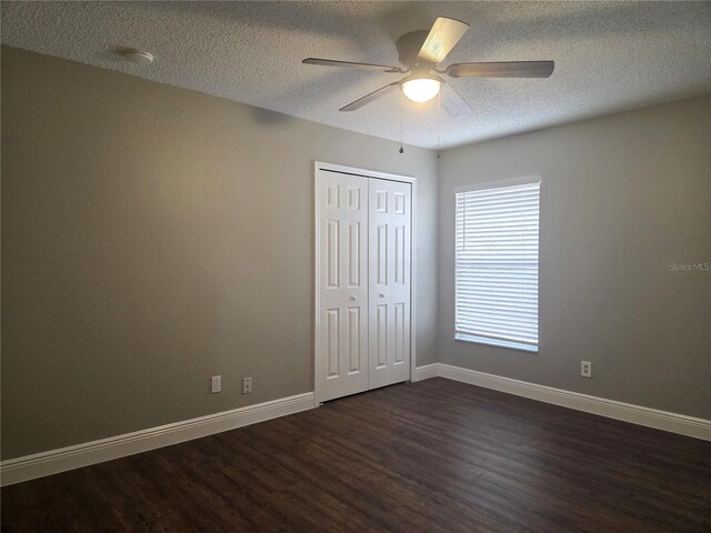 unfurnished room featuring dark wood finished floors, a textured ceiling, baseboards, and ceiling fan