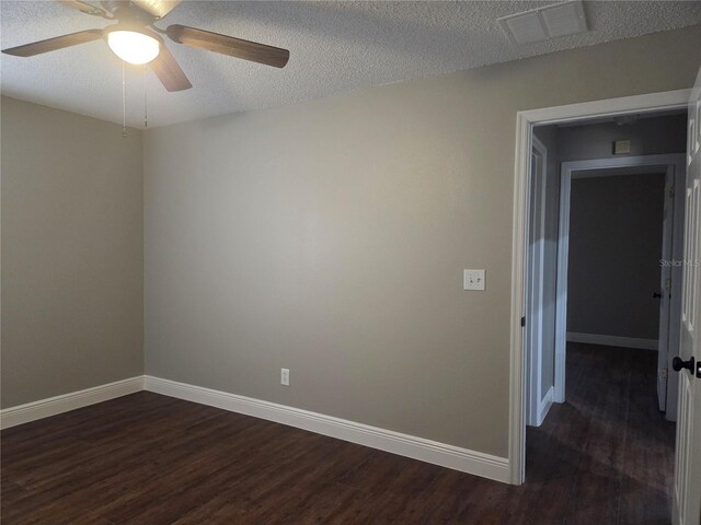 empty room featuring dark wood finished floors, a ceiling fan, baseboards, and a textured ceiling