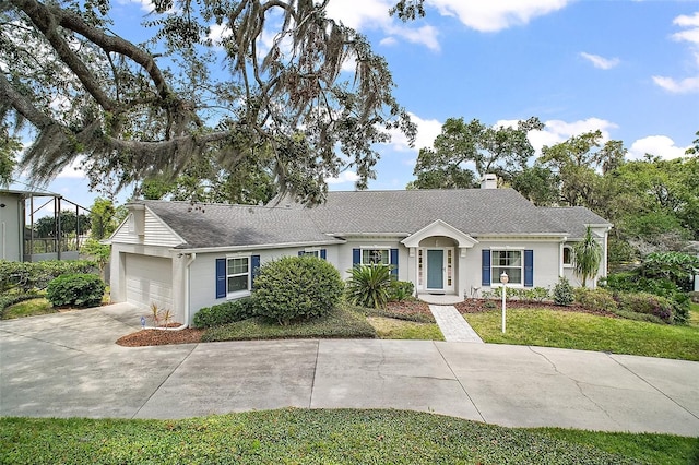 ranch-style home featuring roof with shingles, a front lawn, a garage, a chimney, and driveway