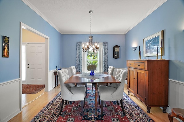 dining room featuring an inviting chandelier, ornamental molding, and light wood finished floors
