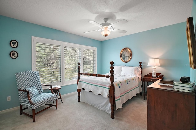 bedroom featuring baseboards, a textured ceiling, ceiling fan, and light carpet