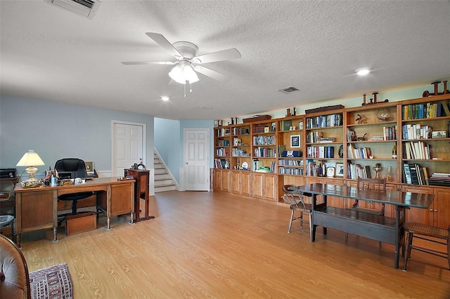 office with a ceiling fan, a textured ceiling, visible vents, and light wood-style flooring