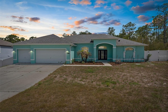 11344 Gallinule Ave, Weeki Wachee, FL 34613 - view of front facade with fence, an attached garage, stucco siding, concrete driveway, and a lawn