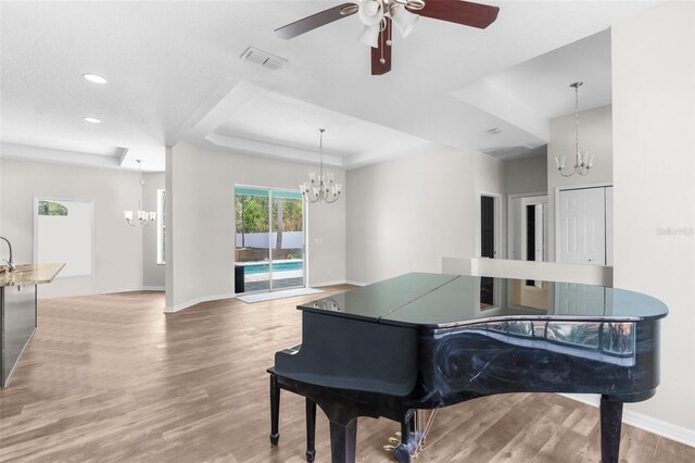 11344 Gallinule Ave, Weeki Wachee, FL 34613 - interior space featuring visible vents, baseboards, light wood-type flooring, a raised ceiling, and ceiling fan with notable chandelier