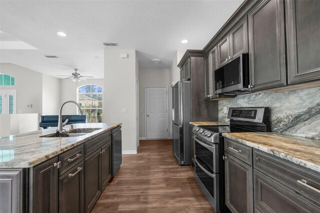 11344 Gallinule Ave, Weeki Wachee, FL 34613 - kitchen with light stone counters, appliances with stainless steel finishes, a sink, dark wood-type flooring, and backsplash