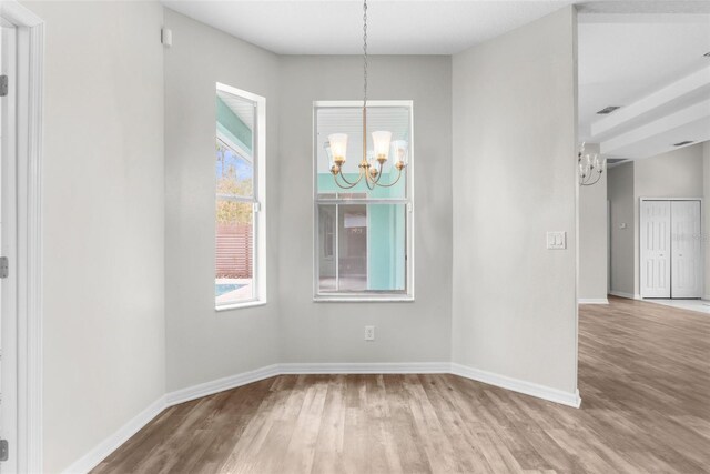 11344 Gallinule Ave, Weeki Wachee, FL 34613 - unfurnished dining area featuring baseboards, visible vents, wood finished floors, and a notable chandelier