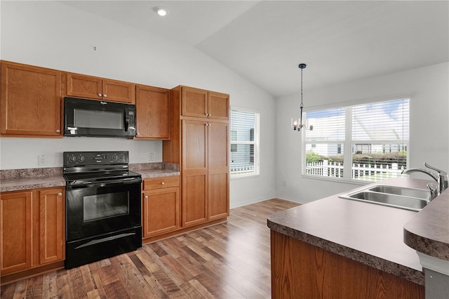 kitchen with brown cabinetry, vaulted ceiling, wood finished floors, a sink, and black appliances