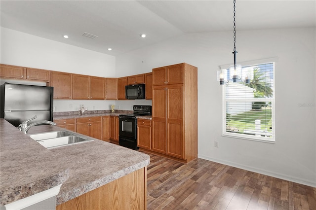 kitchen featuring a sink, light wood finished floors, decorative light fixtures, visible vents, and black appliances