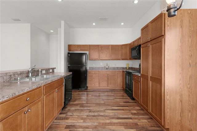 kitchen featuring recessed lighting, a sink, black appliances, and wood finished floors