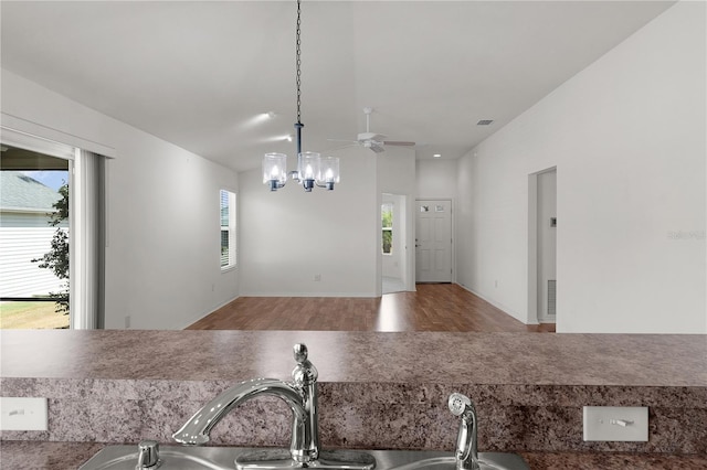 kitchen featuring visible vents, wood finished floors, elevator, a sink, and ceiling fan with notable chandelier