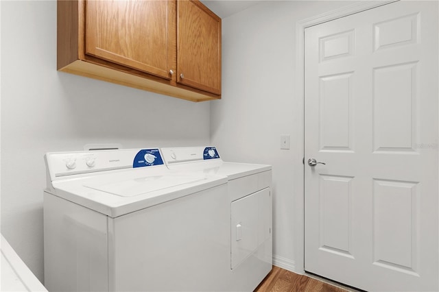laundry room featuring washer and clothes dryer, cabinet space, and light wood-style flooring