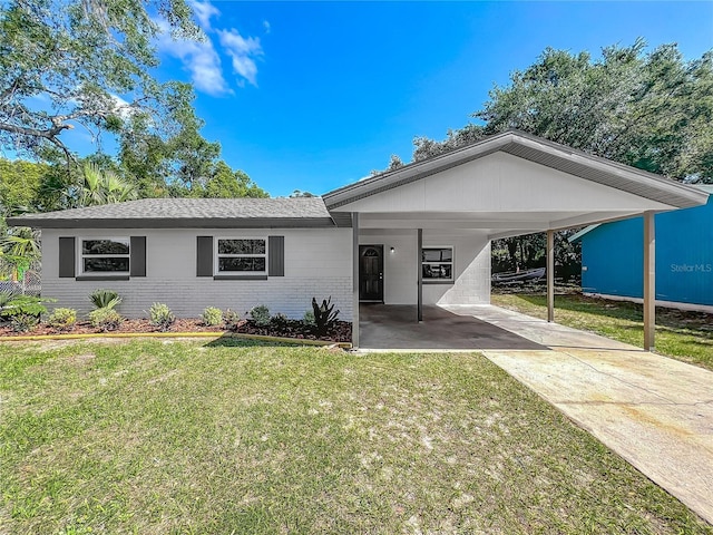 single story home with a front yard, an attached carport, brick siding, a shingled roof, and concrete driveway