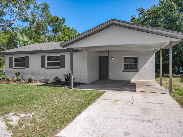 single story home with brick siding, a front lawn, roof with shingles, and a carport