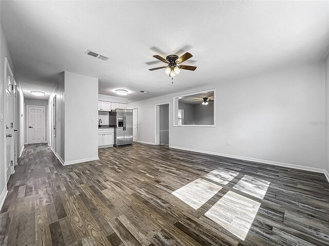 unfurnished living room featuring visible vents, a ceiling fan, baseboards, and dark wood-type flooring