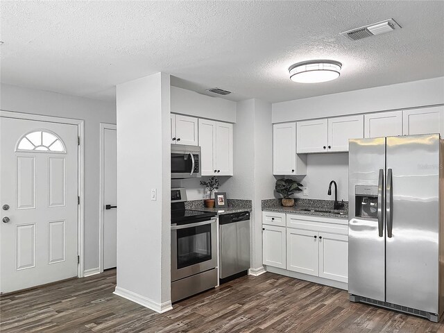 kitchen with visible vents, a sink, dark wood-style floors, and stainless steel appliances