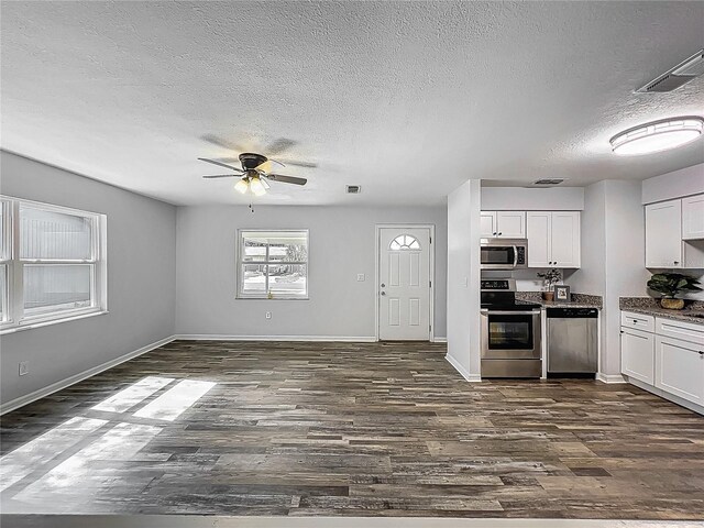 kitchen with appliances with stainless steel finishes, ceiling fan, dark wood finished floors, and a textured ceiling