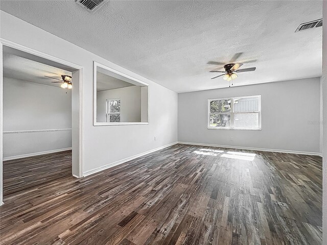 spare room featuring a ceiling fan, dark wood-style floors, a textured ceiling, and visible vents
