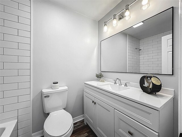 full bathroom with toilet, baseboards, wood finished floors, and vanity